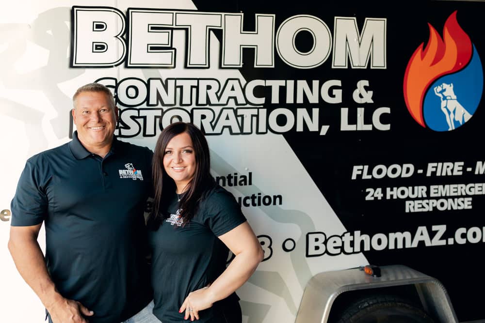 Bethom owners next to a company trailer with company logo